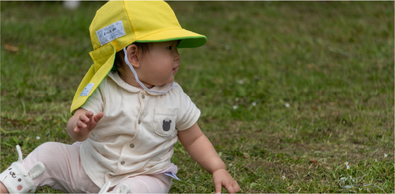 写真:乳児1名が芝生の上で遊んでいる